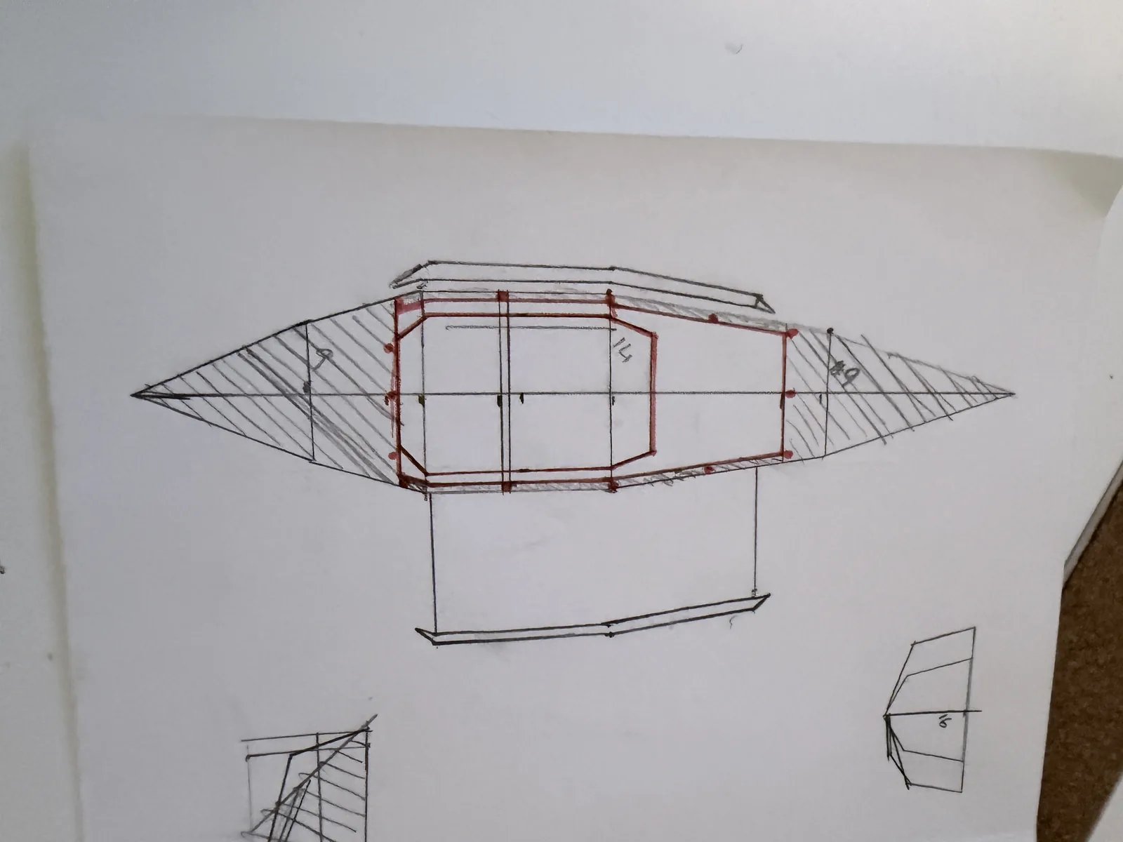 A hand drawing on white paper of a kayak in plan view, hatched at bow and stern, with a red outline marking the deck opening