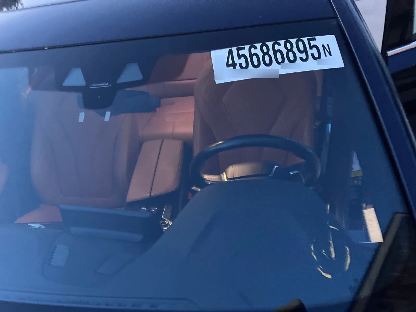 A white sticker with the number 45686895 on the inside of the windshield, with the cognac seats visible through the glass