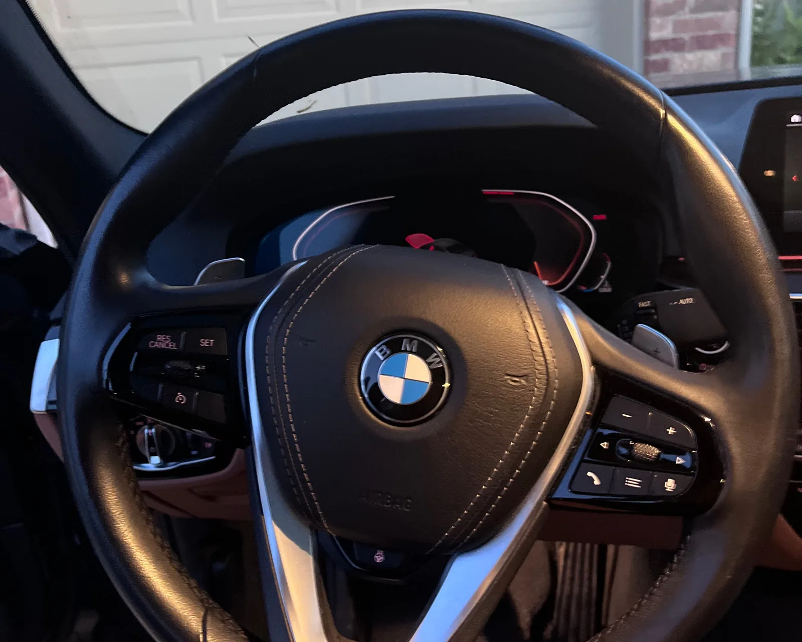A black leather BMW steering wheel with silver trim on the lower spoke, seen from the driver's seat