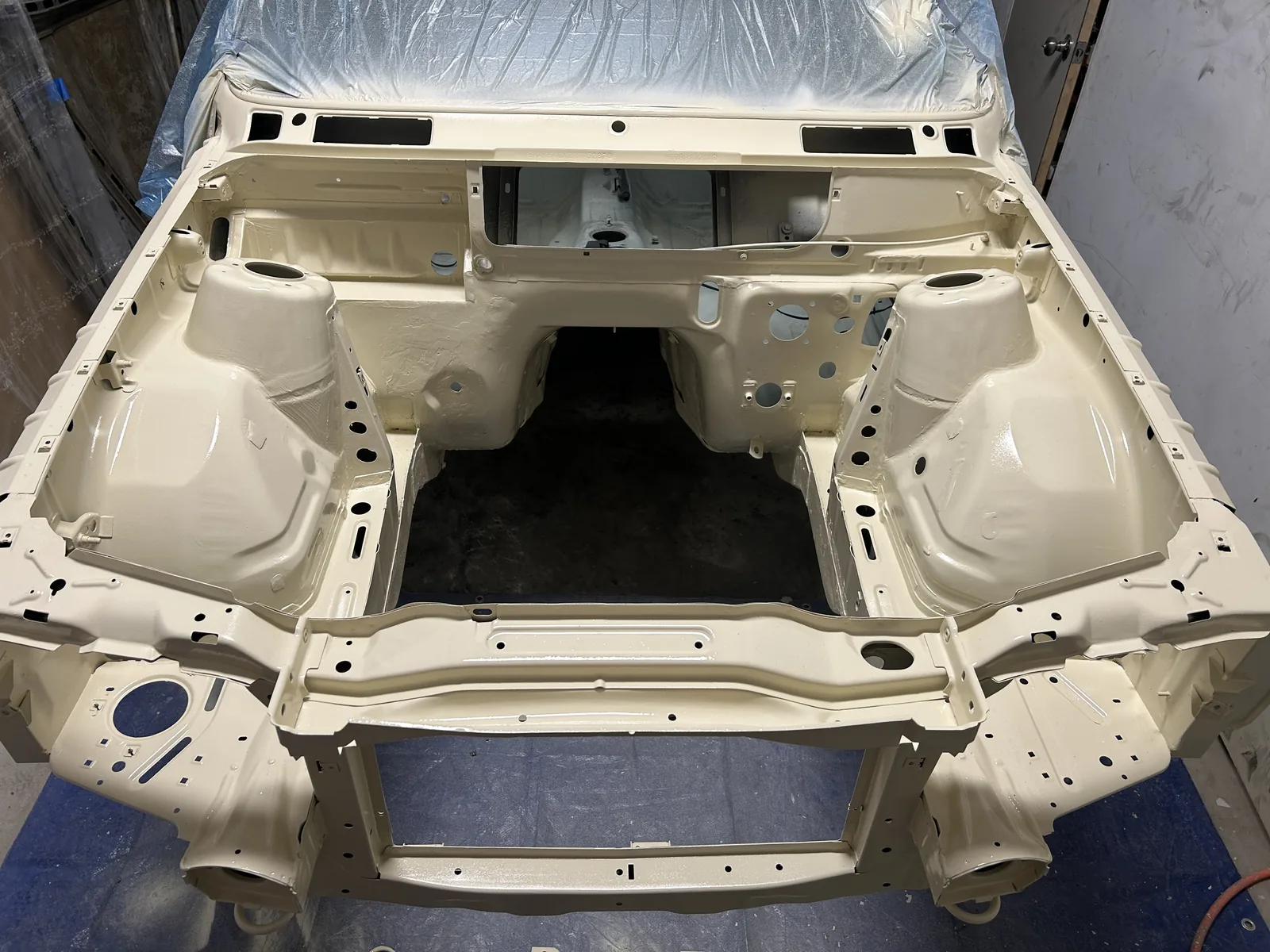 The same engine bay sprayed in the car's cream body colour, clean and glossy, with every seam and hole visible