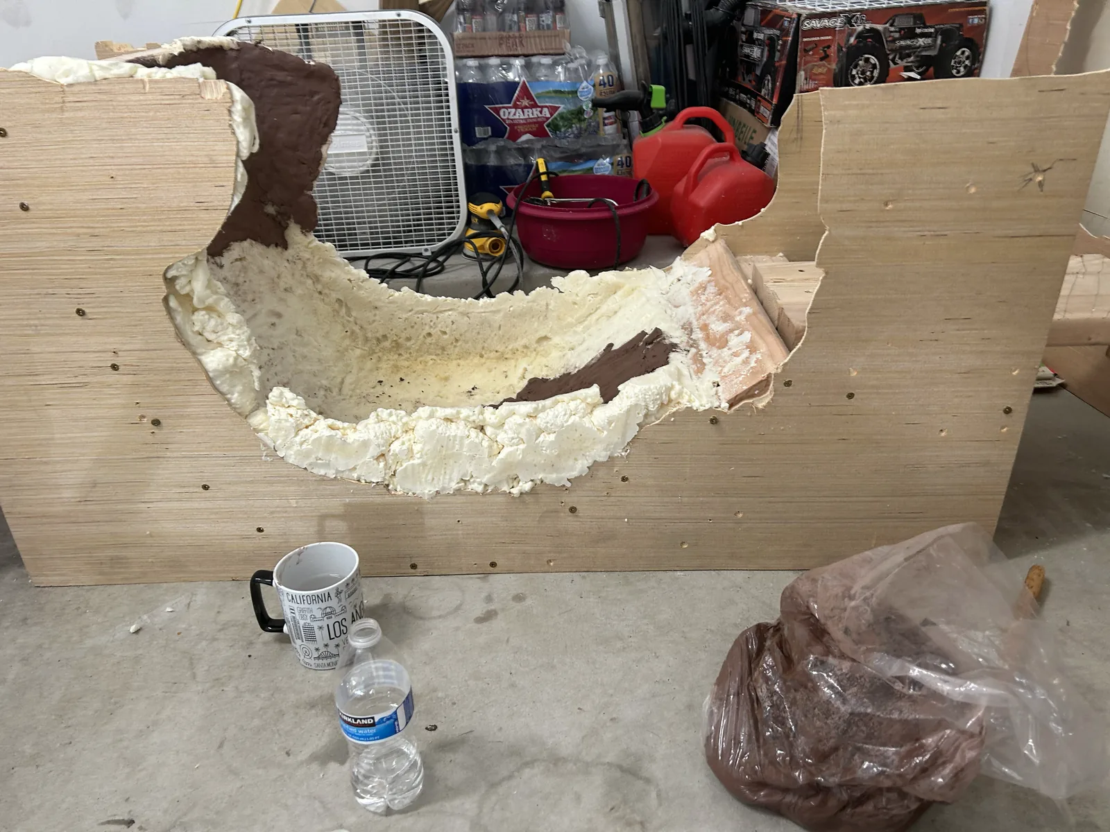 A plywood box filled with rigid foam carved into a seat curve, with brown clay packed into low spots
