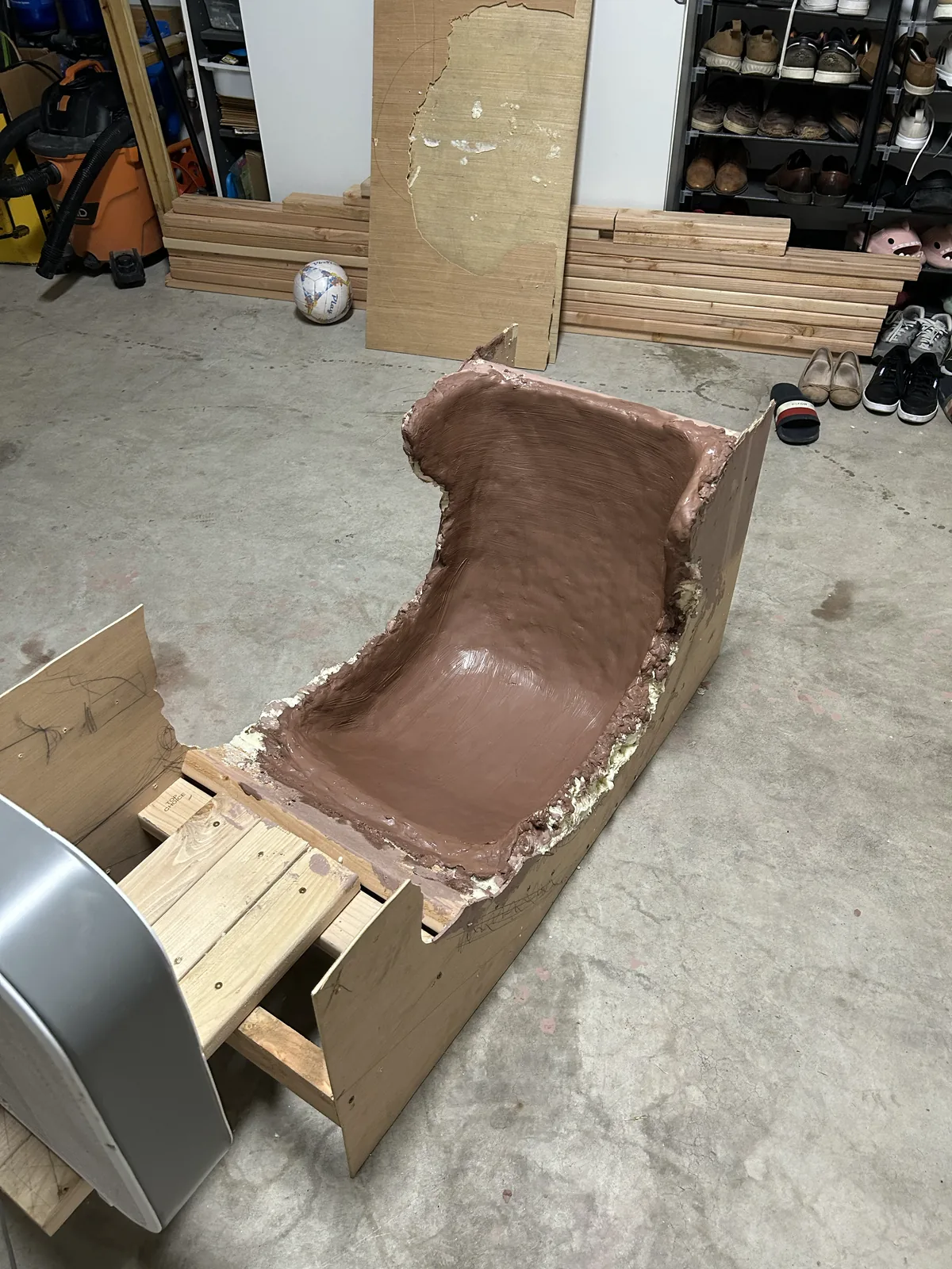 A smoothed brown clay seat plug set into a wooden frame in a garage