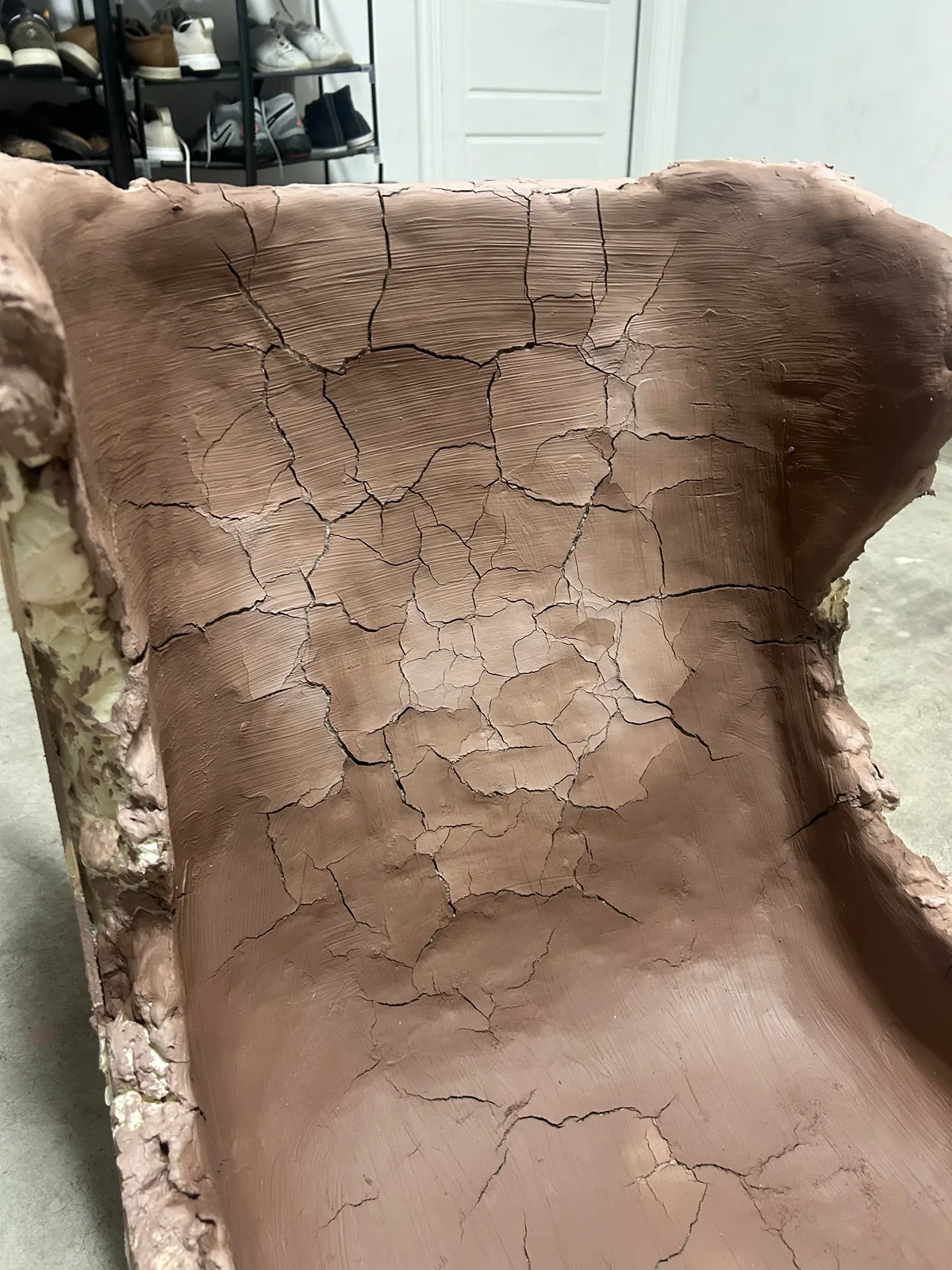 Close up of a clay seat surface covered in a dense network of drying cracks
