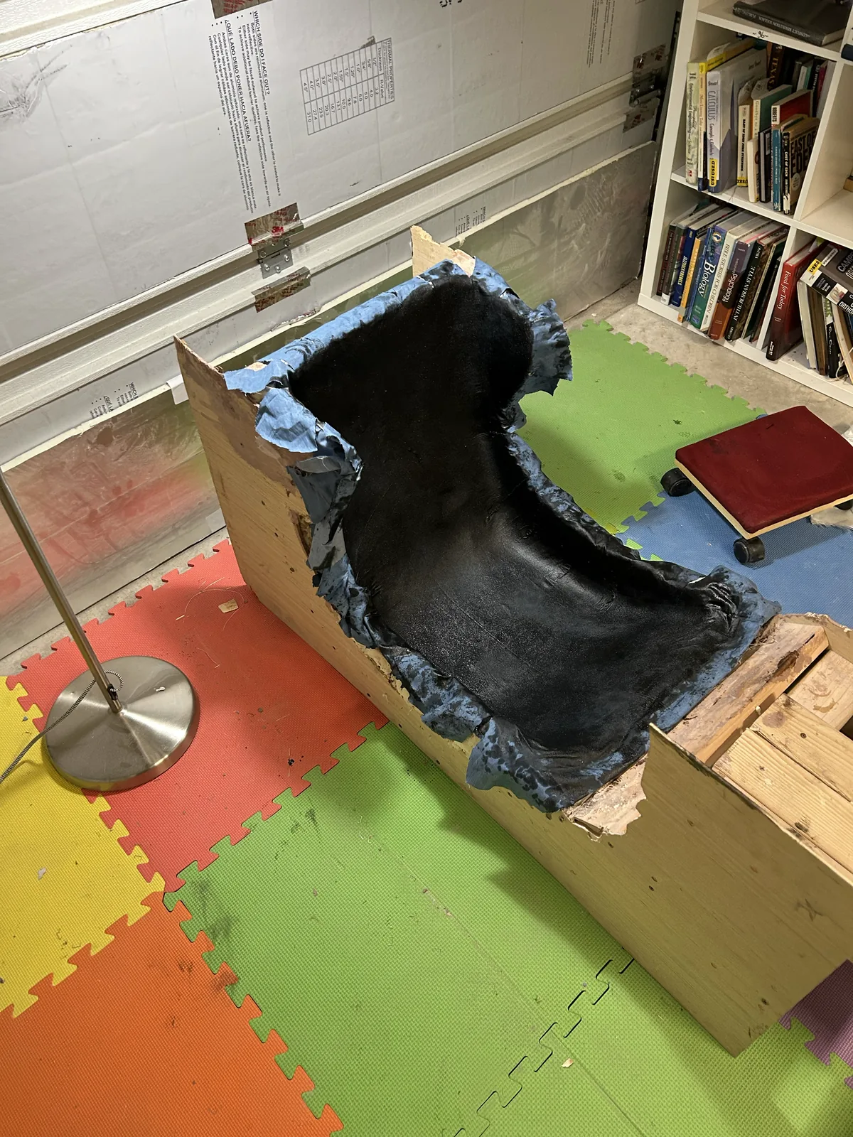 Black chopped carbon fiber and resin pressed into a blue seat mold on a wooden frame