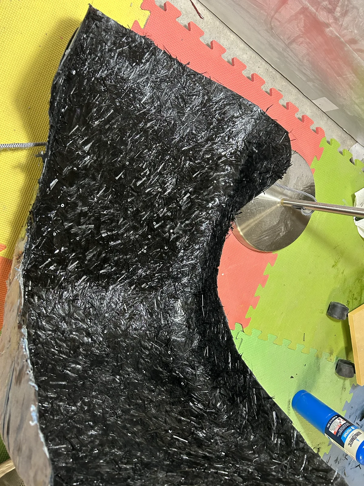 Close up of a glossy black forged carbon surface with a swirling marbled fiber pattern