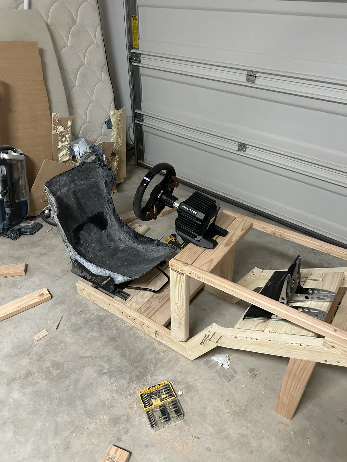 The carbon seat bolted to a rough timber frame in a garage with a sim racing wheelbase attached
