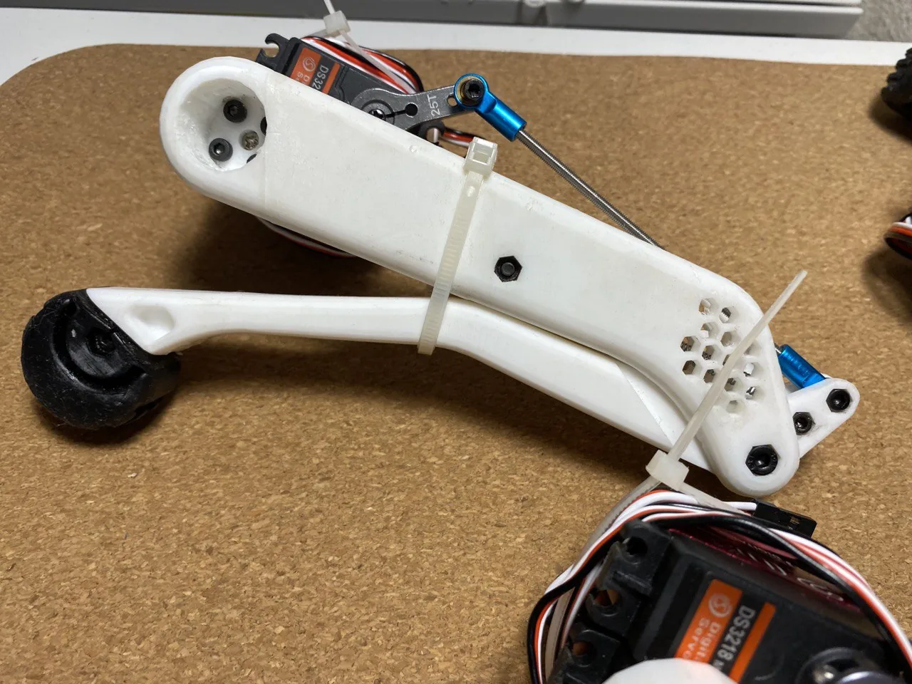 Close up of a 3D printed robot leg with a thin metal pushrod running from a servo to the lower leg