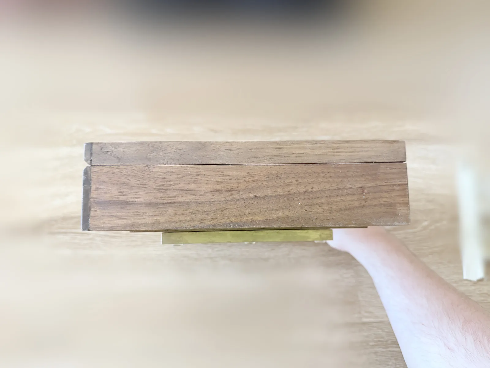 A close square on view of the closed jewelry box from the front, showing the lid overhanging the base slightly and the thin shadow line between them