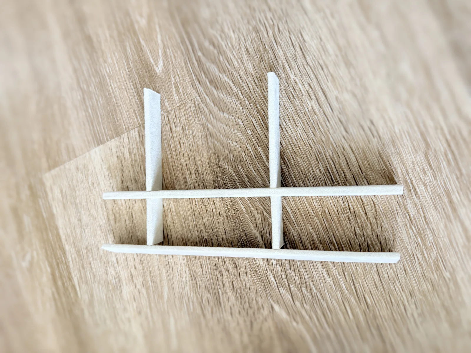 A short section of divider lattice on a wood floor, cream strips crossing at right angles with a notched halving joint at each intersection