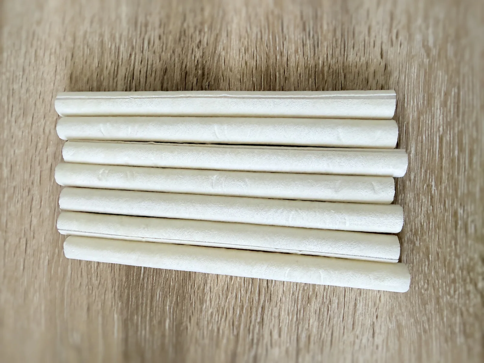 Seven cream coloured padded fabric rolls laid side by side on a wood floor