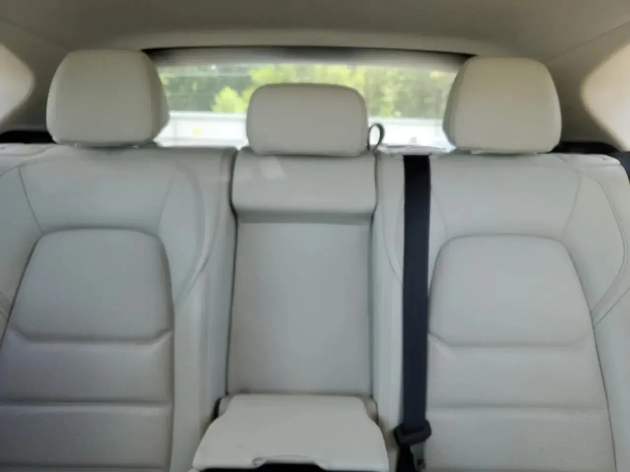 The CX-5's rear bench in light grey leather, with three headrests and the rear window behind them