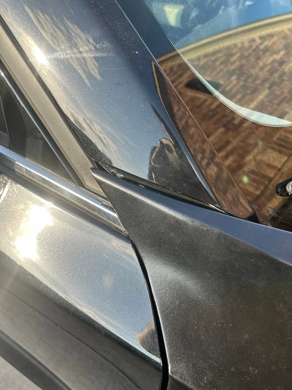 A tighter close-up of the joint between the top of the fender and the door frame at the base of the windshield, with dust on the panels