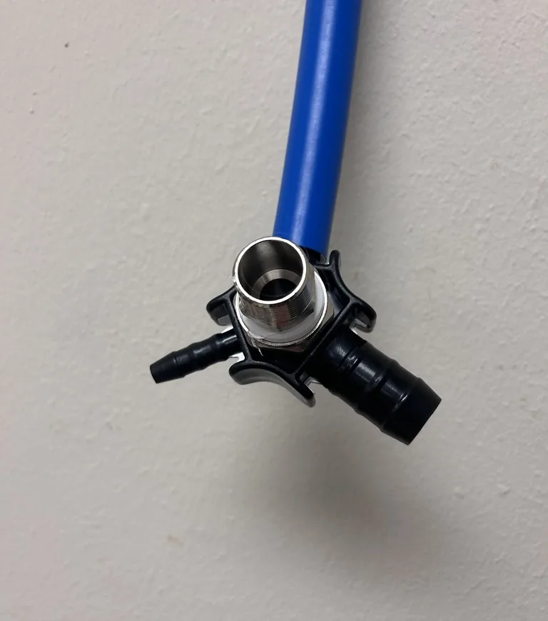 A close view of a blue air line ending in a black plastic wall bracket with a metal sleeve and two black barbed ports